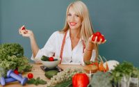 Healthy lifestyle concept with woman holding tomatoes and surrounded by fresh vegetables in a studio setting.